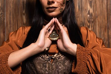 cropped view of woman with steampunk makeup touching medallion on woodenの写真素材