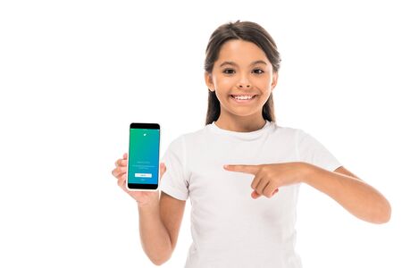 KYIV, UKRAINE - SEPTEMBER 3, 2019: happy kid pointing with finger at smartphone with twitter app on screen isolated on whiteのeditorial素材
