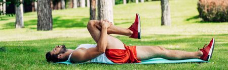 panoramic shot of bearded athletic man working out on fitness matの写真素材