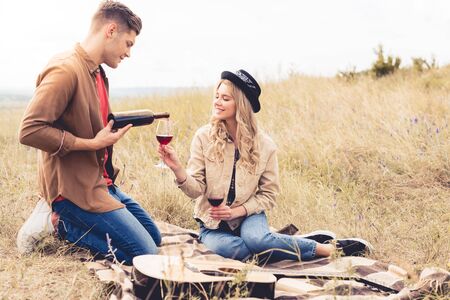 handsome and smiling man pouring wine to glass outsideの写真素材