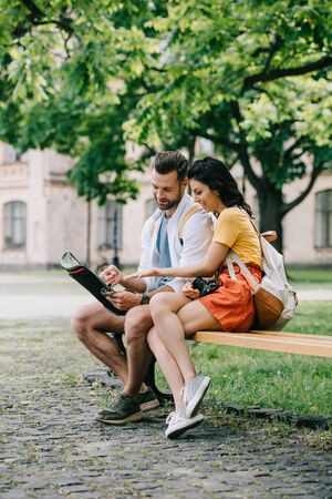 cheerful woman gesturing near map and handsome manの写真素材