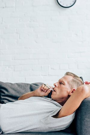 side view of handsome man smoking blunt with medical cannabis in apartmentの写真素材