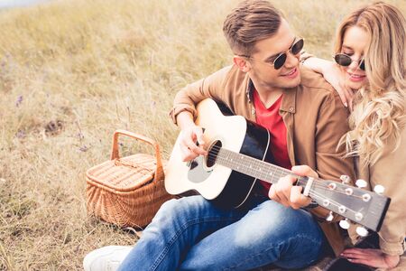 handsome man playing acoustic guitar and attractive woman hugging himの写真素材