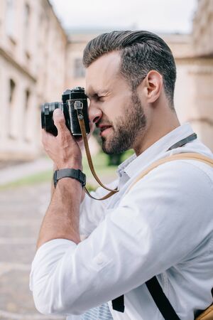 side view of bearded man taking photo on digital cameraの写真素材