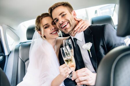 attractive bride and handsome bridegroom hugging and clinking with champagne glasses