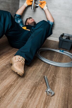 selective focus of bearded repairman fixing water damage in sinkの写真素材