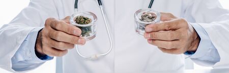 panoramic shot of doctor in white coat holding pills and medical cannabis isolated on whiteの写真素材