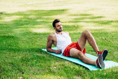 handsome sportsman lying on fitness man in parkの写真素材