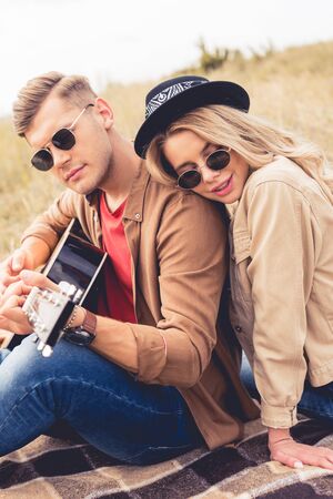 handsome man playing acoustic guitar and attractive woman hugging him