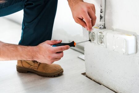 cropped view of repairman sitting while fixing power