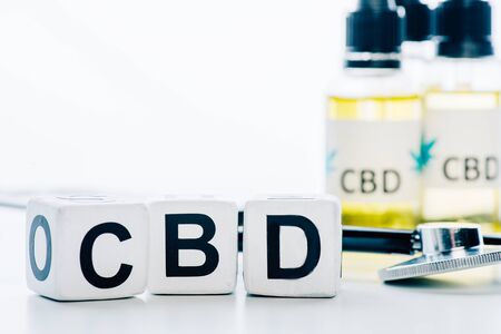 selective focus of cannabis oil in bottles with lettering cbd, cubes and stethoscope on white backgroundの写真素材