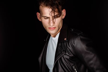 stylish young man in leather jacket isolated on blackの写真素材