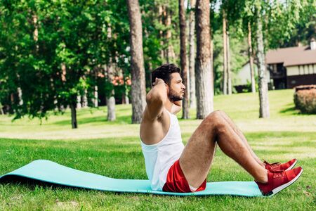side view of bearded sportsman doing do abs on fitness matの写真素材