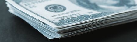 panoramic shot of stack with dollar banknotes on black