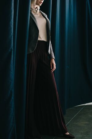 cropped view of elegant woman in palazzo pants standing near curtainの写真素材