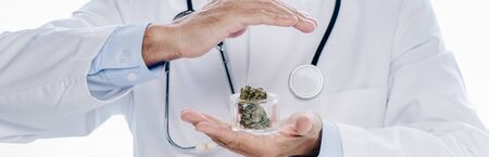 panoramic shot of doctor in white coat holding medical cannabis and pills isolated on whiteの写真素材