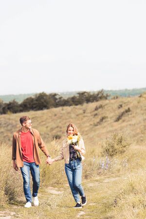 attractive woman with bouquet and handsome man smiling and holding handsの写真素材