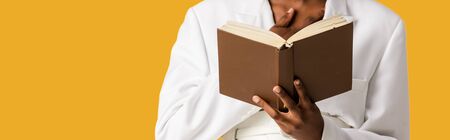 panoramic shot of african american woman holding book isolated on orange