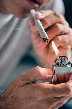 cropped view of man lighting up blunt with medical cannabis