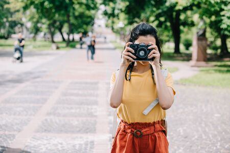 young woman covering face while taking photo on digital cameraの写真素材