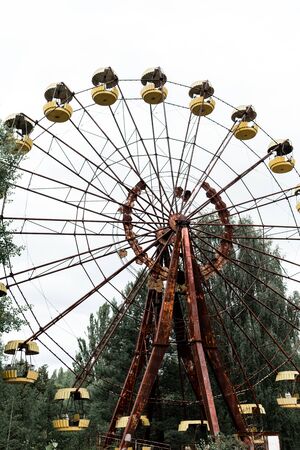 abandoned and rusty carousel in amusement park with trees against skyの写真素材
