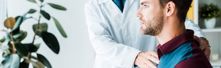 panoramic shot of doctor in white coat touching handsome patientの写真素材