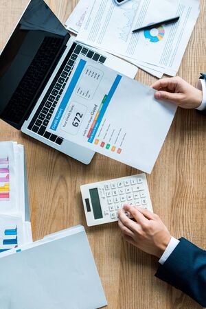 top view of businessman holding document with letters near calculator and laptop