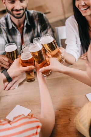 partial view of multicultural friends clinking glasses of light beer in pubの写真素材