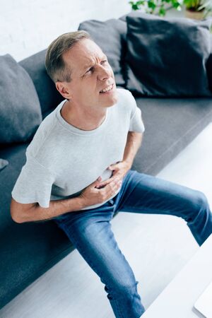 high angle view of handsome man in t-shirt with stomachacheの写真素材