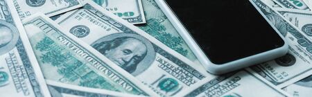 panoramic shot of smartphone with blank screen on dollar banknotes