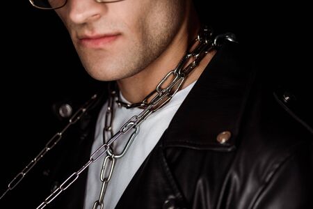 cropped view of man with metallic chains on neck isolated on blackの写真素材