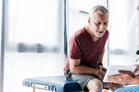 cropped view of doctor holding digital tablet near mature patientの写真素材