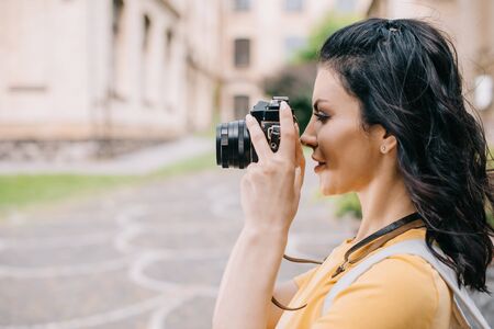 side view of attractive girl holding digital camera while taking photoの写真素材