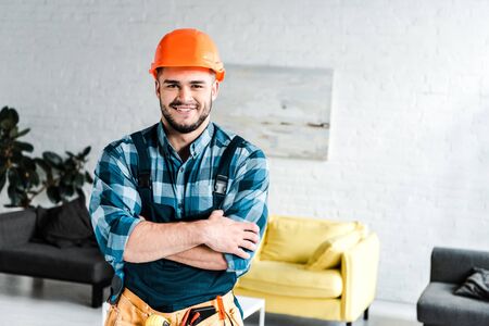 happy handyman looking at camera while standing with crossed arms