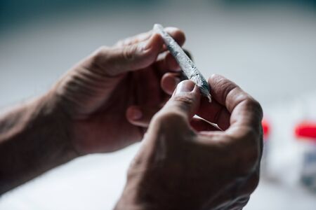 cropped view of man rolling blunt with medical cannabisの写真素材