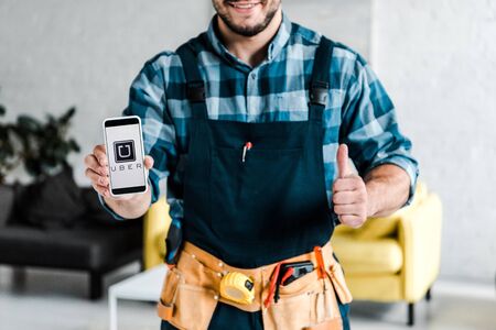 KYIV, UKRAINE - JULY 31, 2019: cropped view of happy man holding smartphone with uber app on screen and showing thumb upのeditorial素材