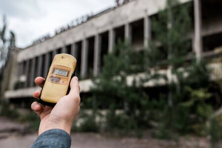 PRIPYAT, UKRAINE - AUGUST 15, 2019: cropped view of man holding radiometer near building in chernobylのeditorial素材