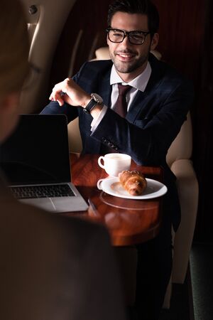 professional businesspeople working with laptop, coffee and croissant sitting in plane