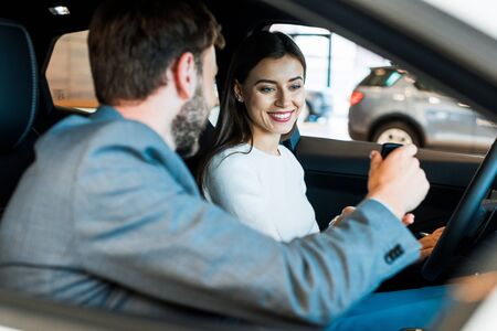 selective focus of cheerful woman looking at car key in hand of bearded manの写真素材
