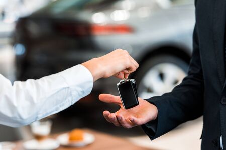 cropped view of car dealer giving car key to manの写真素材
