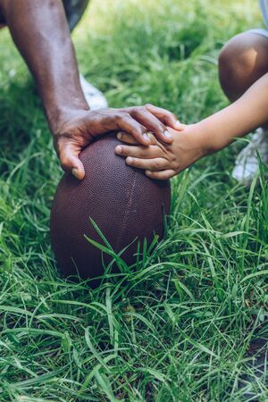 cropped view of african american father and son touching rugby ballの写真素材