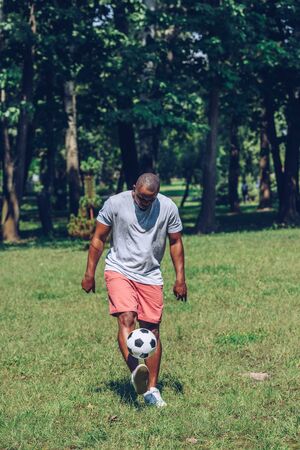 young, sportive african american man playing football in parkの写真素材