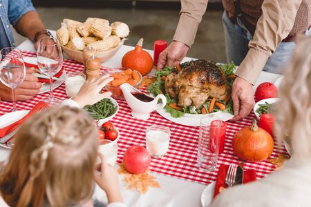 cropped view of grandfather putting on table plate with turkey in Thanksgiving dayの写真素材