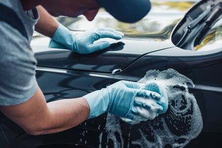 partial view of car cleaner washing car with sponge and detergentの写真素材