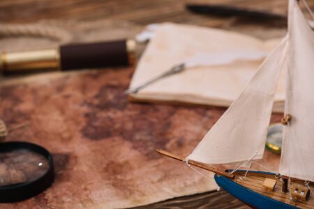 crafted ship near old world map with magnifying glass and telescope