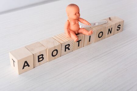 baby doll near pregnancy test and wooden cubes with lettering on wooden table
