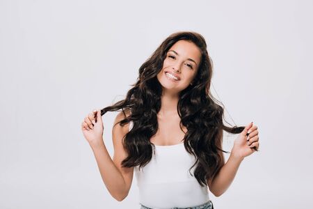 happy brunette beautiful woman with long curly healthy hair isolated on grey