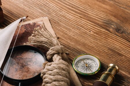 world map, rope cable, compass and magnifying glass on wooden surfaceの写真素材