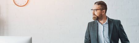 panoramic shot of handsome businessman in formal wear and glasses looking awayの写真素材