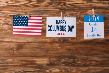 card with happy Columbus day inscription near American national flag and calendar paper sheet with 14 October date on wooden surfaceの写真素材